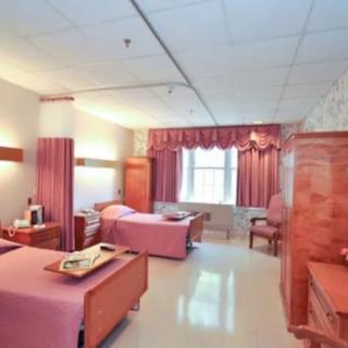 A spacious hospital room with two beds and pink decor.