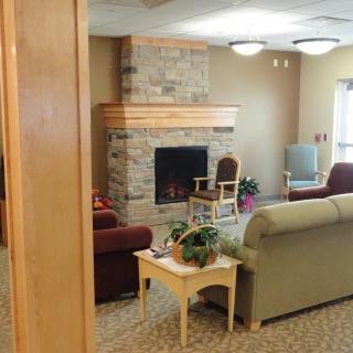 A cozy living room featuring a stone fireplace, comfortable seating, and indoor plants.