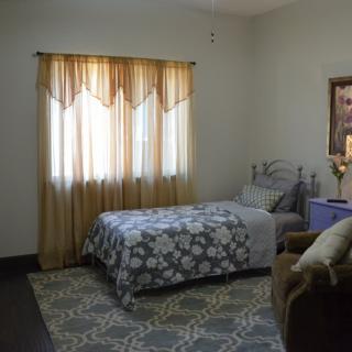 A cozy bedroom with a single bed, floral bedding, and warm curtains.