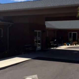 A sunny day view of a building entrance with a driveway and canopy.