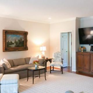 A cozy living room featuring a comfortable sofa, a wall-mounted television, and elegant artwork.