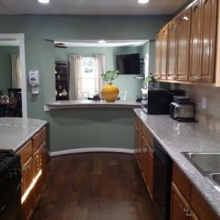 A modern kitchen with wooden cabinets and appliances, featuring a sleek design and green walls.