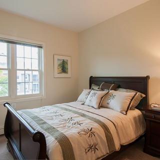 A cozy bedroom with a neatly made bed and soft lighting.