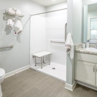 An accessible bathroom with safety features such as grab bars and a shower seat.