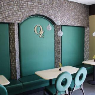 A modern restaurant interior featuring a green color scheme with stylish seating and pendant lighting.