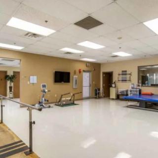 A rehabilitation center therapy room with exercise equipment and parallel bars.