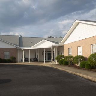 A view of a building with a white entrance and cloudy skies above.