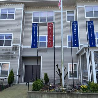 An entrance to a modern apartment building adorned with multiple flags.