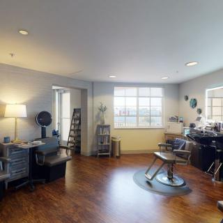 A modern and spacious hair salon interior with styling chairs and equipment.