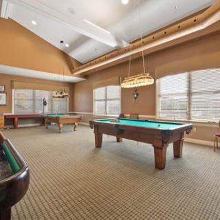 A spacious game room featuring billiards tables and large windows.