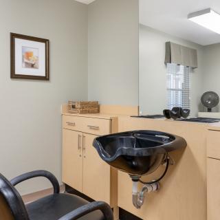 A hair salon setup with a chair, sink, and wooden cabinets.