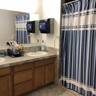 A bathroom with a double sink vanity and blue striped shower curtain.