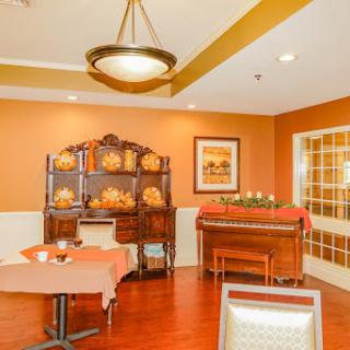 A cozy dining area featuring warm tones, elegant furniture, and a piano, perfect for gatherings.
