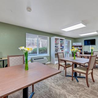 A calm dining area with wooden tables, chairs, and decorative flowers in vases.