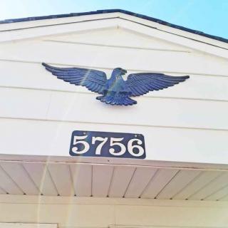 A house with an eagle decoration above the address number 5756.