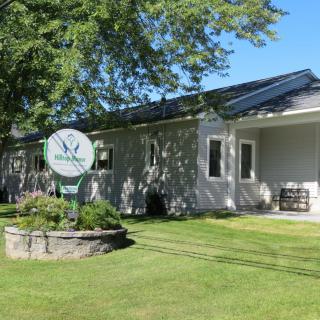 A house with a well-maintained lawn and a garden, featuring a satellite dish in the yard.