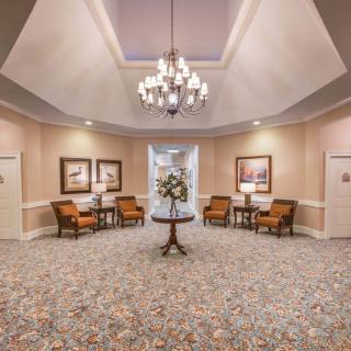 A spacious lobby with elegant decor, featuring a chandelier and comfortable seating.