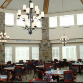 A spacious dining room with multiple chandeliers, tables, and chairs.