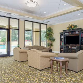 A cozy living room with comfortable sofas, a TV, and large windows.