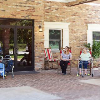 Seniors sitting outside a nursing home enjoying the outdoors.