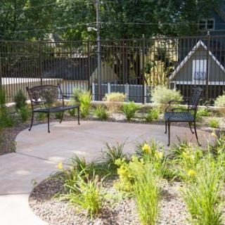 A serene garden area featuring curved pathways and benches surrounded by lush greenery.
