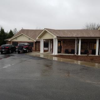 A residential house with parked vehicles on a rainy day.