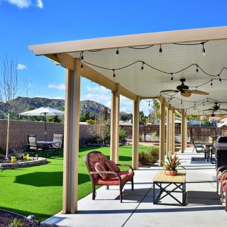 A well-designed patio with comfortable furniture and string lights overlooking a landscaped backyard on a sunny day.
