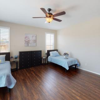 A minimalist bedroom featuring twin beds, hardwood flooring, and a ceiling fan.