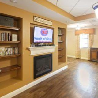 A cozy living room with a fireplace, bookshelves, and a television mounted above the mantel.