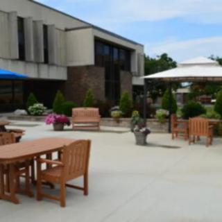 An outdoor patio area featuring wooden tables and chairs, large umbrellas, and potted plants.