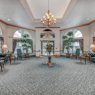 Elegant lobby with a central chandelier, seating area, and large windows.