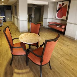 A cozy lounge area featuring a round table with four orange chairs and abstract artwork on the wall.