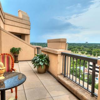 A cozy balcony with scenic views and comfortable seating, featuring decorative plants and a vibrant chair.