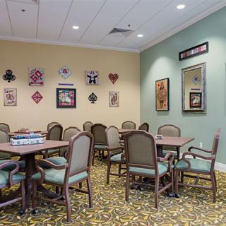 A furnished meeting room with tables and chairs, adorned with wall decorations and artwork.