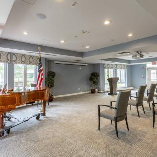A well-lit conference room setup with chairs, a podium, and an American flag near the windows.