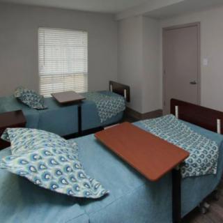 A shared room with two hospital beds, equipped with overbed tables.