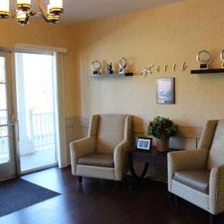 A cozy waiting area featuring comfortable chairs, decorative trophies, and natural light.