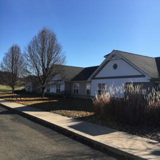 A peaceful residential building surrounded by trees under a clear blue sky.