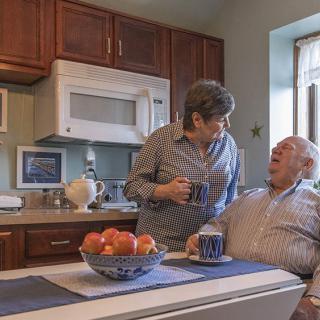 An elderly couple enjoying a conversation over coffee in their kitchen.