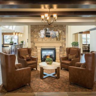 A cozy living room featuring a stone fireplace surrounded by leather chairs and a coffee table.