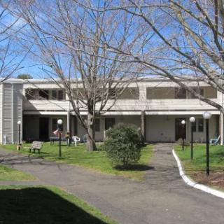 A residential building with a pathway and trees in the foreground.