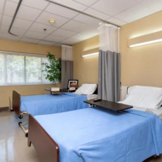 A shared hospital room with two beds, complete with privacy curtains and a window view.