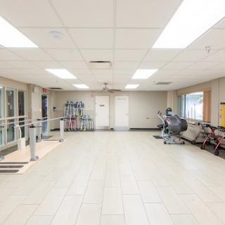 A spacious and well-lit exercise room equipped with various fitness machines.