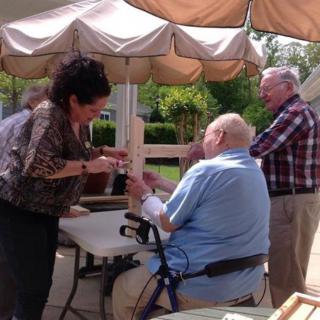A group of people interacting outdoors, with one person using a walker for support.