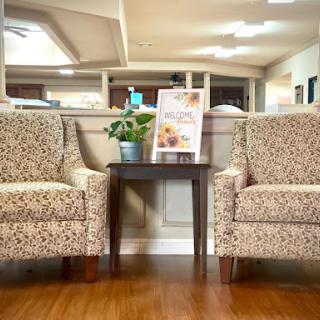 A cozy waiting area featuring patterned chairs and a small table with a plant.