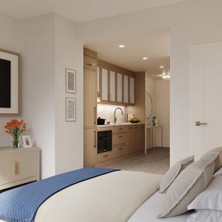 A modern and minimalist bedroom with a view of a kitchenette, featuring neutral tones and decorative art on the walls.