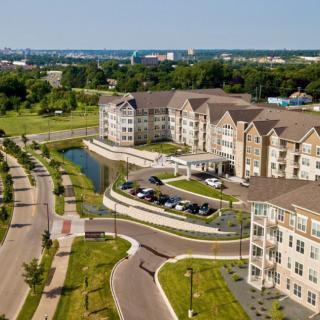 Aerial view of a modern apartment complex surrounded by landscaped roads and greenery.