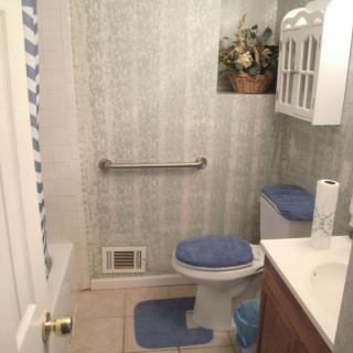 A cozy bathroom with blue accents, featuring a toilet, sink, and towel rack.
