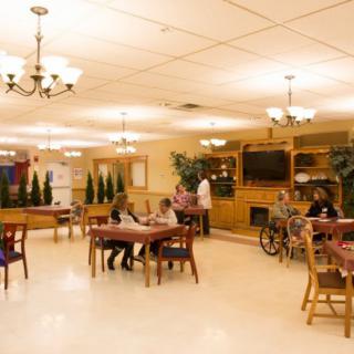 A cozy community area in a senior living facility with residents and caregivers.