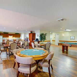 A spacious community room featuring tables and chairs for multiplayer games in an indoor setting.